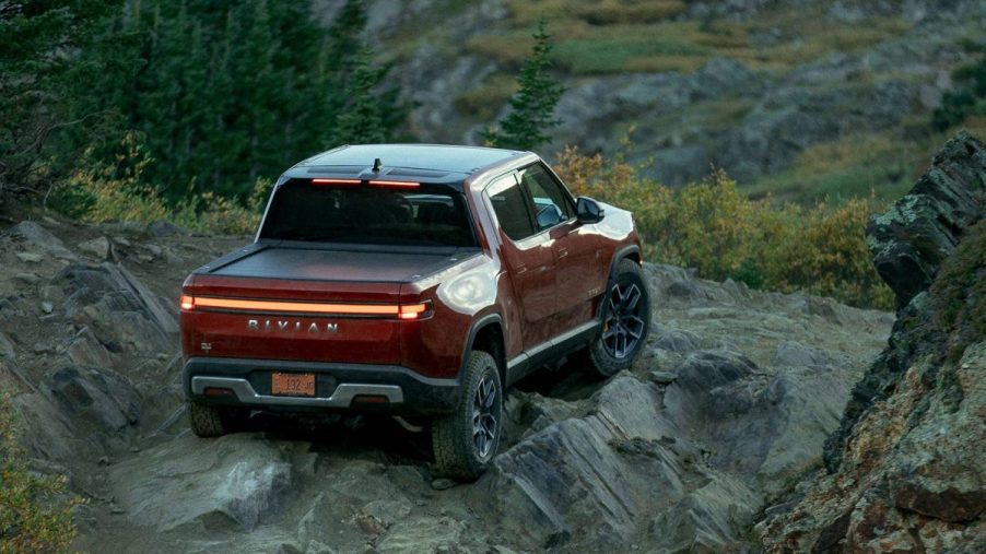 Orange-red 2022 Rivian R1T driving off-road, highlighting advantages of electric vehicles vs. gas-powered cars
