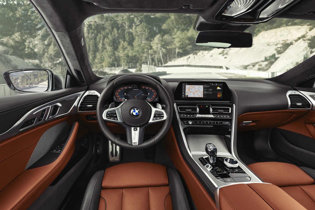 An interior view of a 2022 BMW 8 Series Coupe showing the steering wheel, dashboard, gauges, and infotainment system.