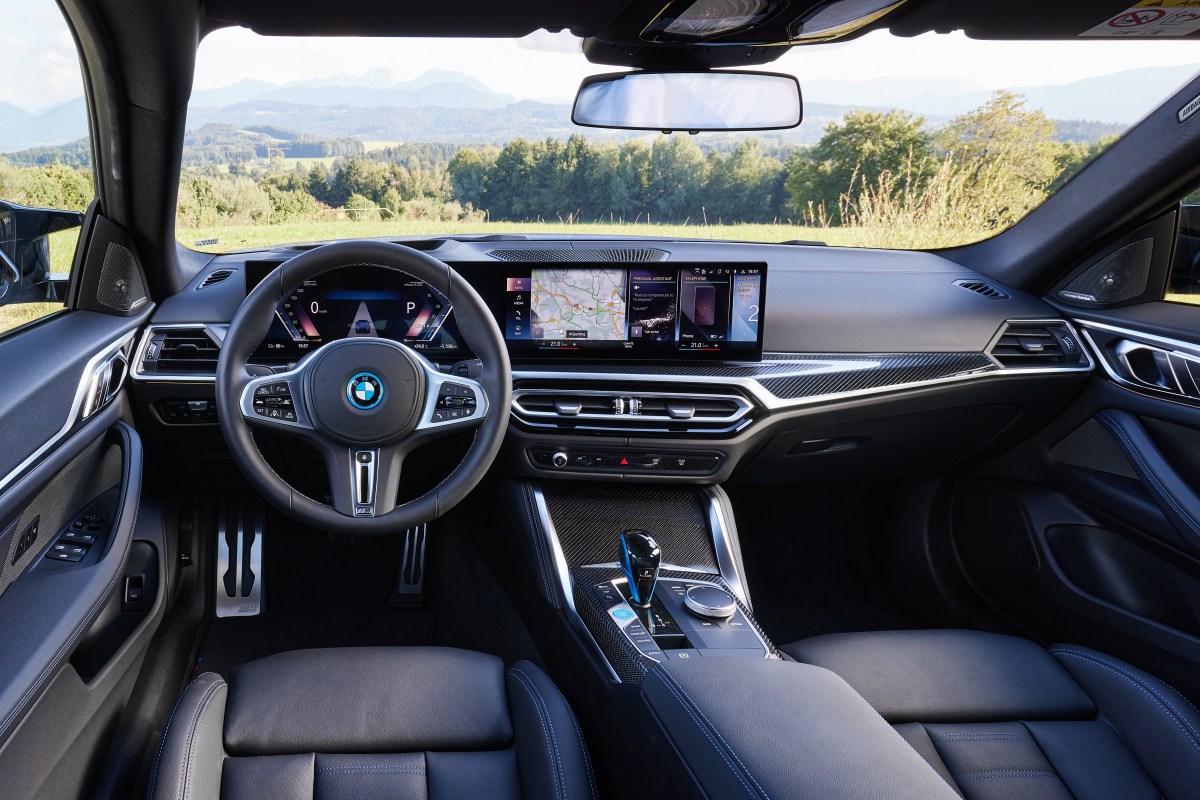 An interior view of a 2022 BMW i4 M50 showing the steering wheel, dashboard and instrument cluster.