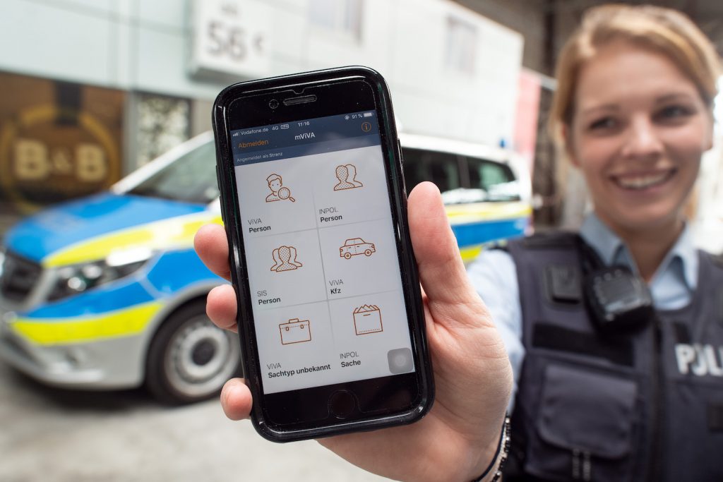 A police officer smiling and holding up a new iPhone to be used by her department.