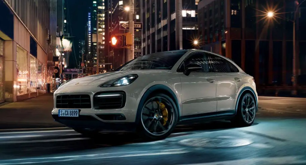 A white 2022 Porsche Cayenne Turbo GT luxury SUV is driving on the road.