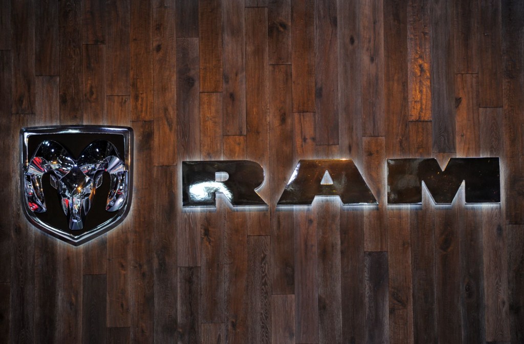 Ram logo on a wood plank background with the letters and symbol in chrome backlite with a white light.