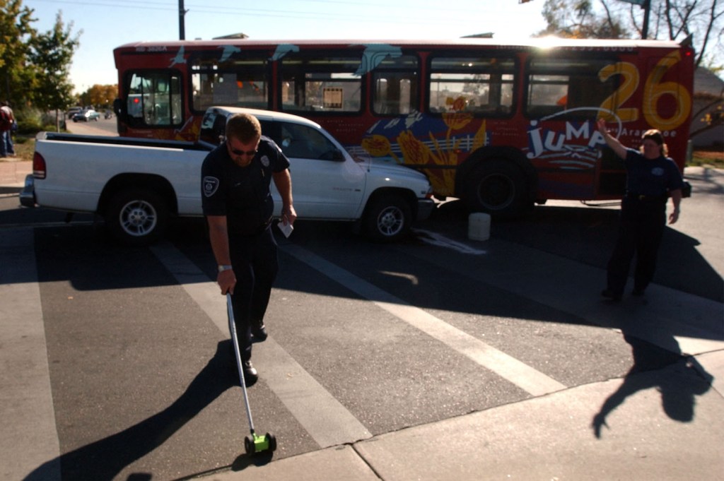 Police officers in front of a Ram truck crashed into a bus.