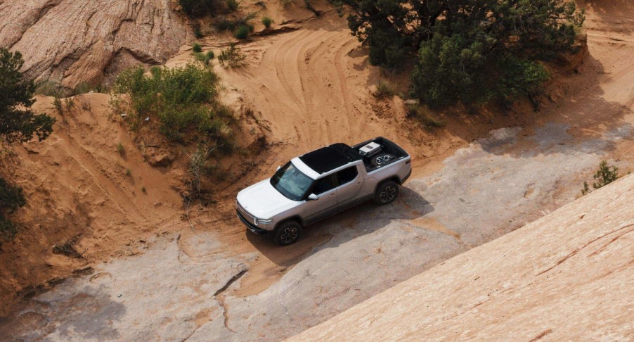 A gray 2022 Rivian R1T is driving off-road.