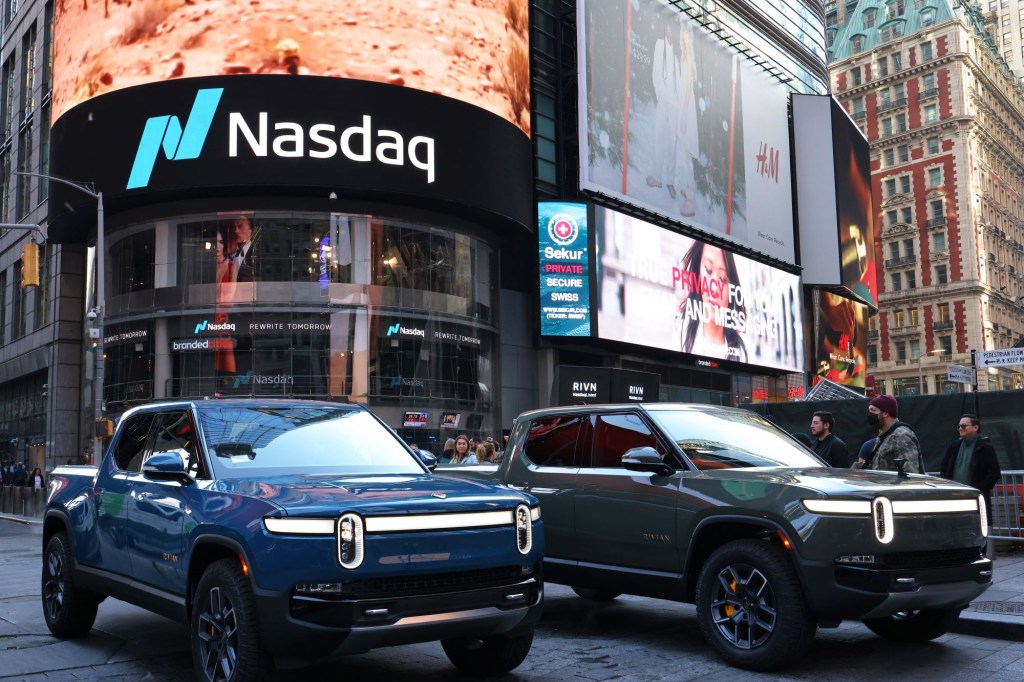 Two Rivian trucks, aided by Ford's Rivian investment, parked in a large city. 