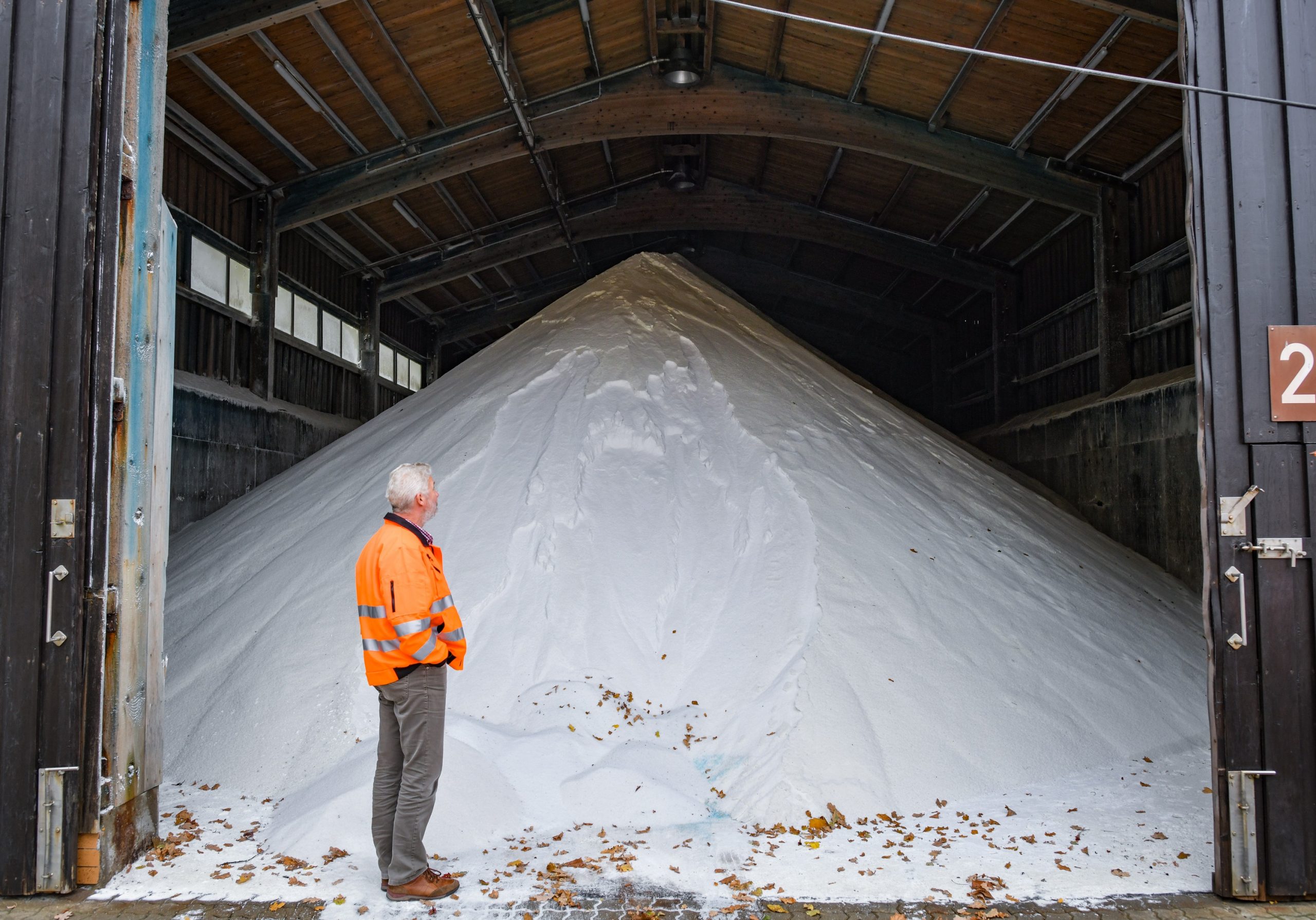 A man stands in front of a massive pile of road salt