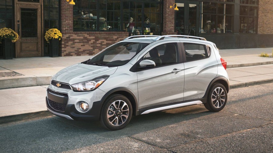 Silver 2022 Chevrolet Spark, the cheapest car available to buy in 2022, parked next to a sidewalk