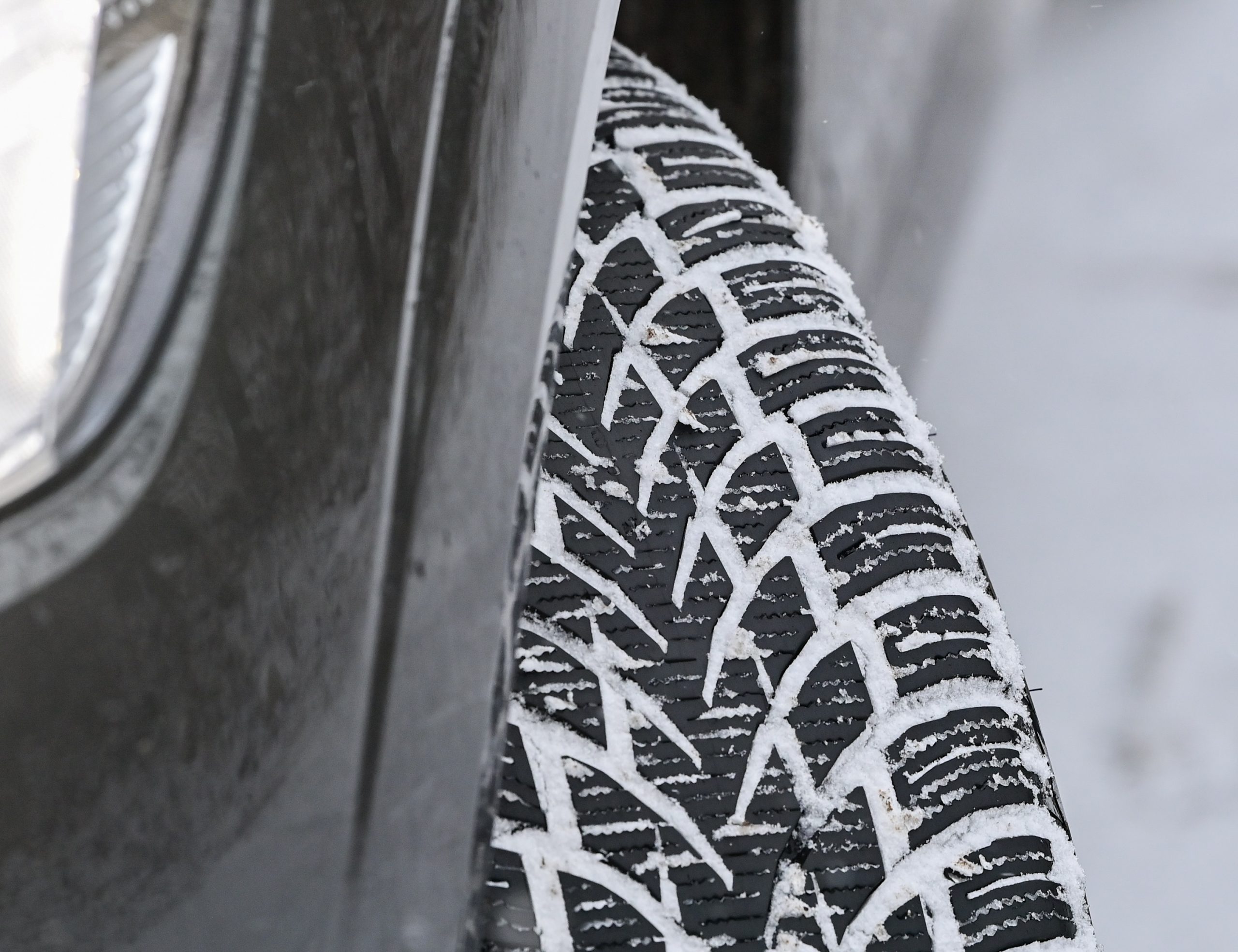 A close up of a car's tires with snow in the treads