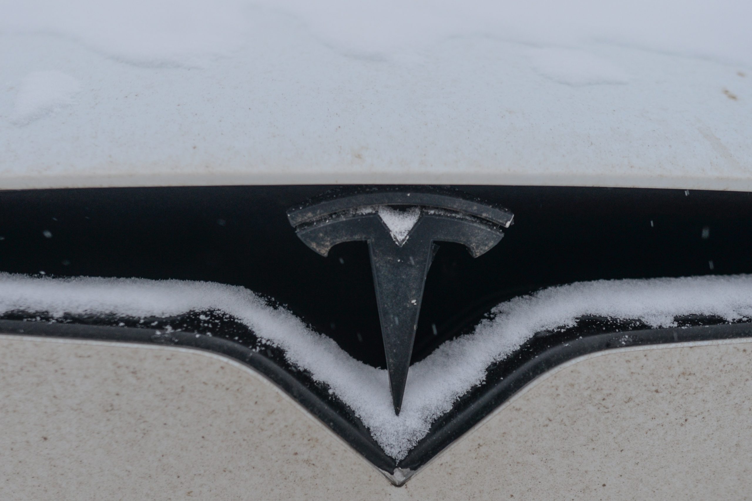A Tesla logo covered in snow on a Model 3