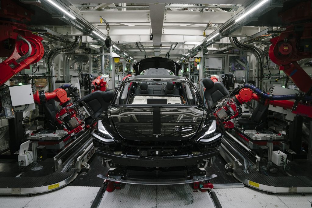 Robots assemble a Tesla Model 3 in one of the brand's factories