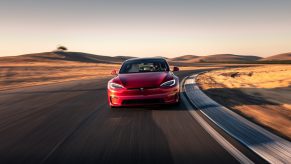 A Tesla Model S Plaid electric car shot from the front on a race track at sunset