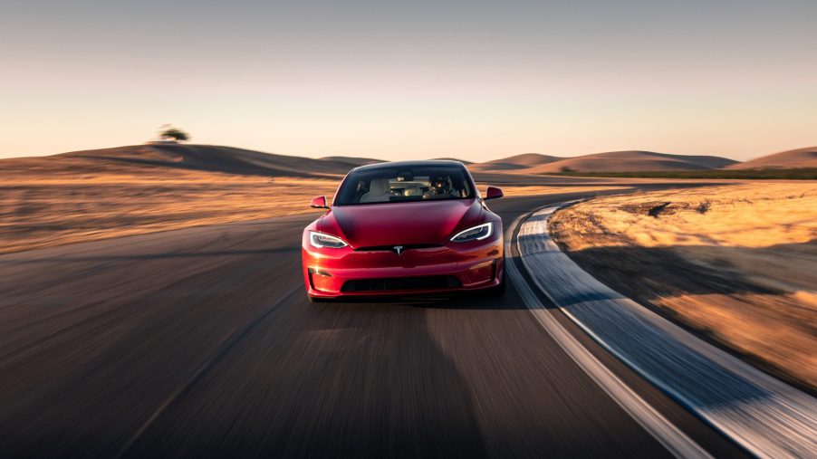 A Tesla Model S Plaid electric car shot from the front on a race track at sunset