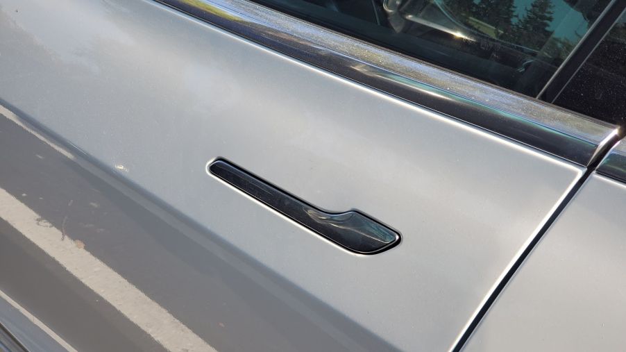 A black Tesla door handle on a silver Tesla.