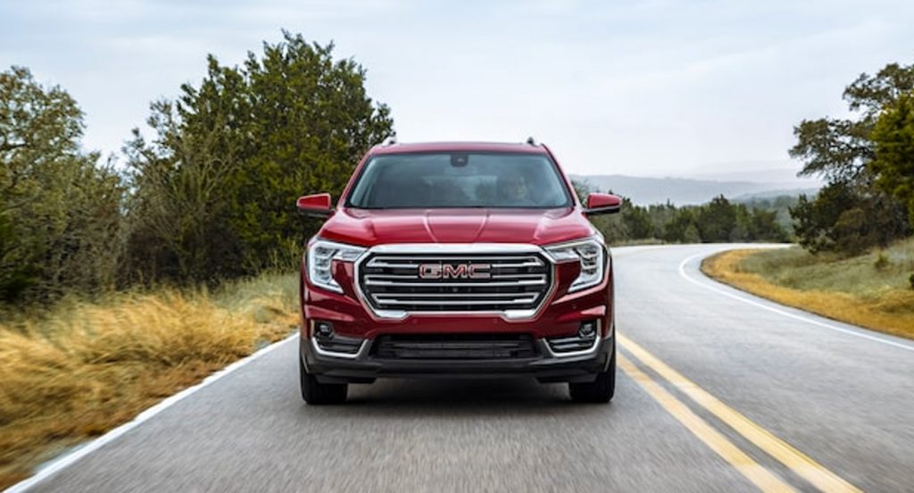 A red 2022 GMC Terrain is driving on the road. 