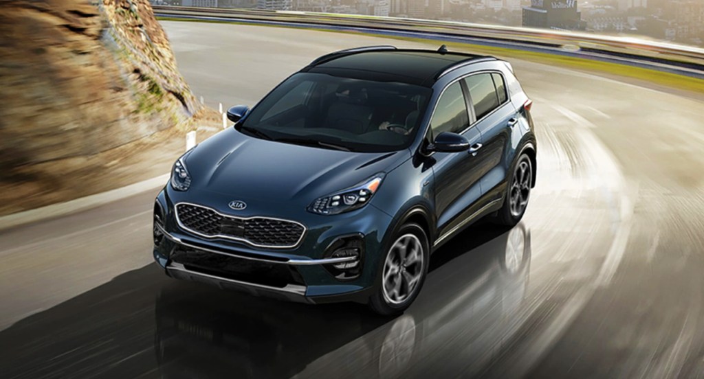 A blue 2022 Kia Sportage is driving on the road.