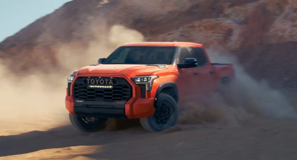 An orange 2022 Toyota Tundra is driving in the sand. 