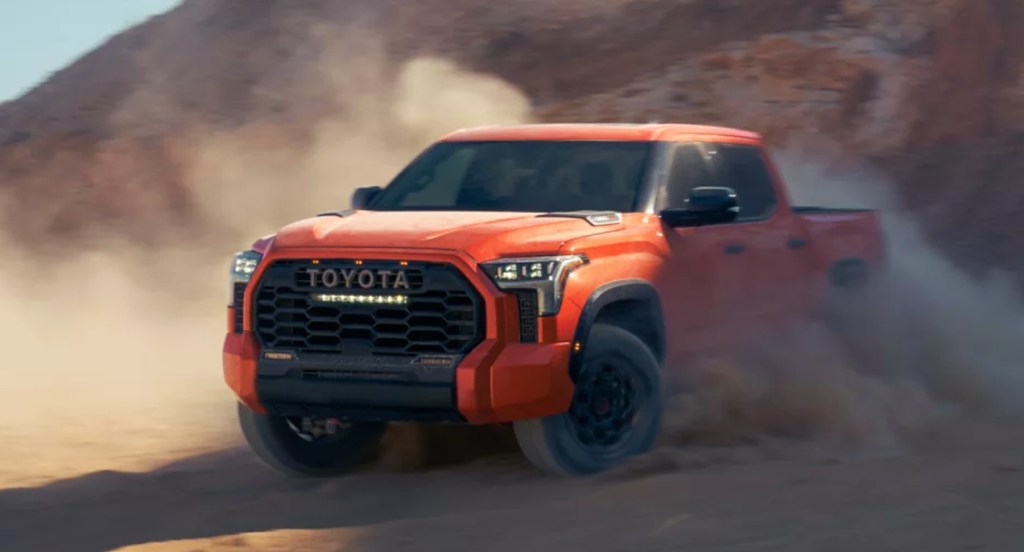 An orange 2022 Toyota Tundra TRD Pro is driving in the sand. 