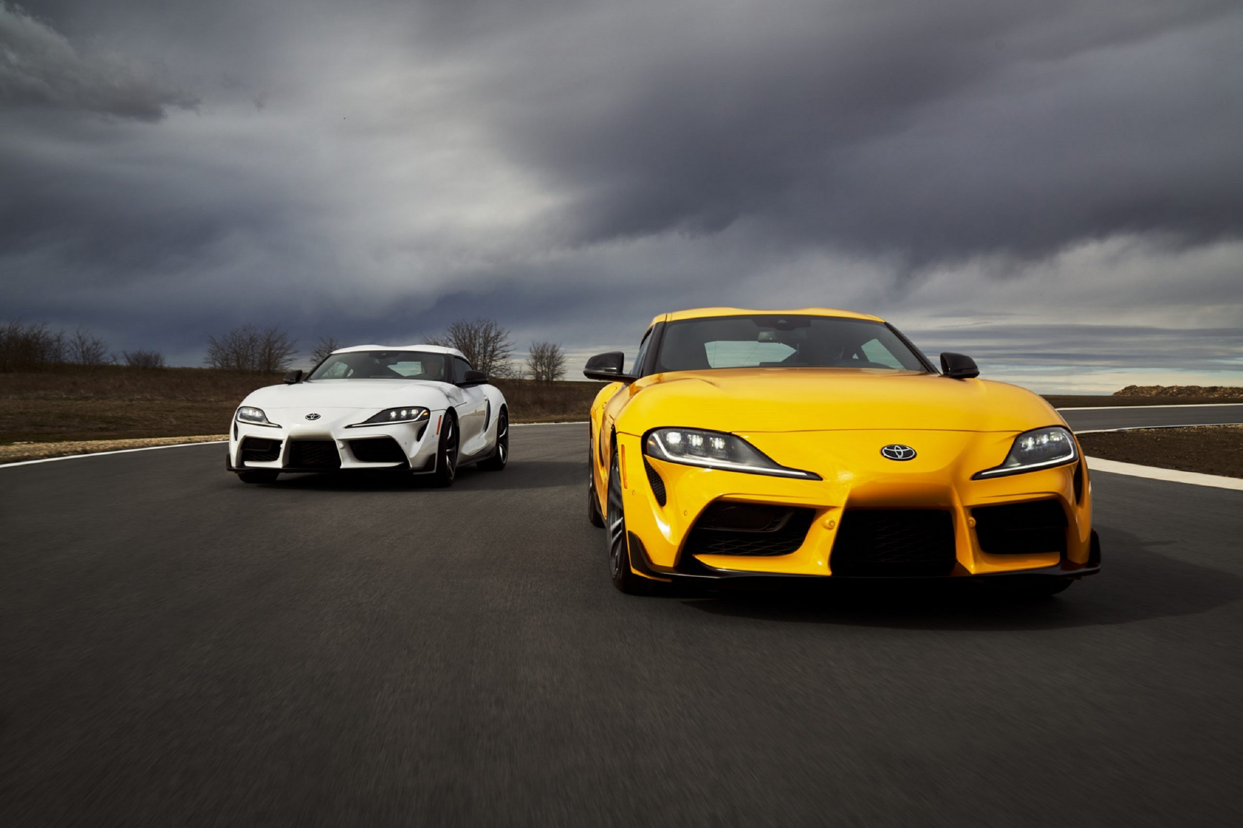 A pair of Toyota Supra sports cars shot from the front on a race track