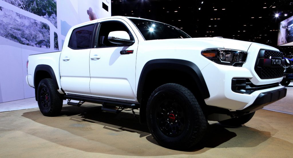 A white Toyota Tacoma midsize truck is on display. 