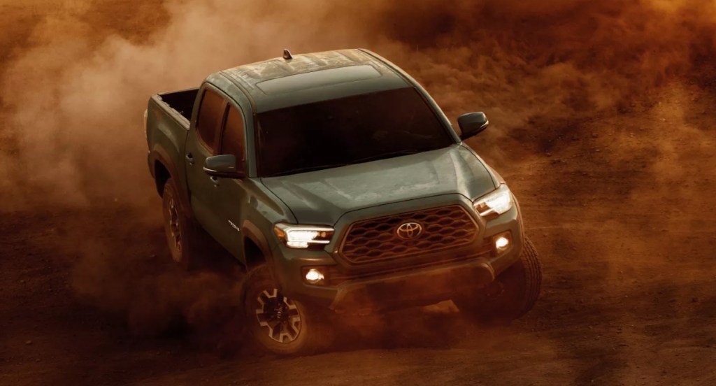 A green Toyota Tacoma is driving off-road.