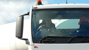 A truck driver in a white semi-truck driving.