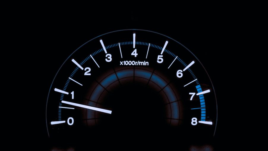 The backlit tachometer of a car that is idling its engine while parked.