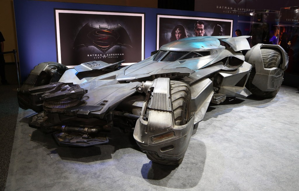 The batmobile prop driven by Ben Affleck parked in front of movie posters at the premier.