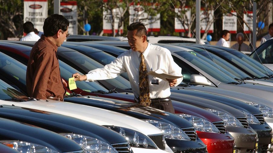 A car salesman and auto expert assists a customer in the lot of a Toyota dealership in El Monte, California