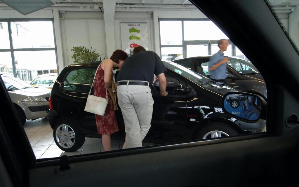 A couple checks out a car in a dealership