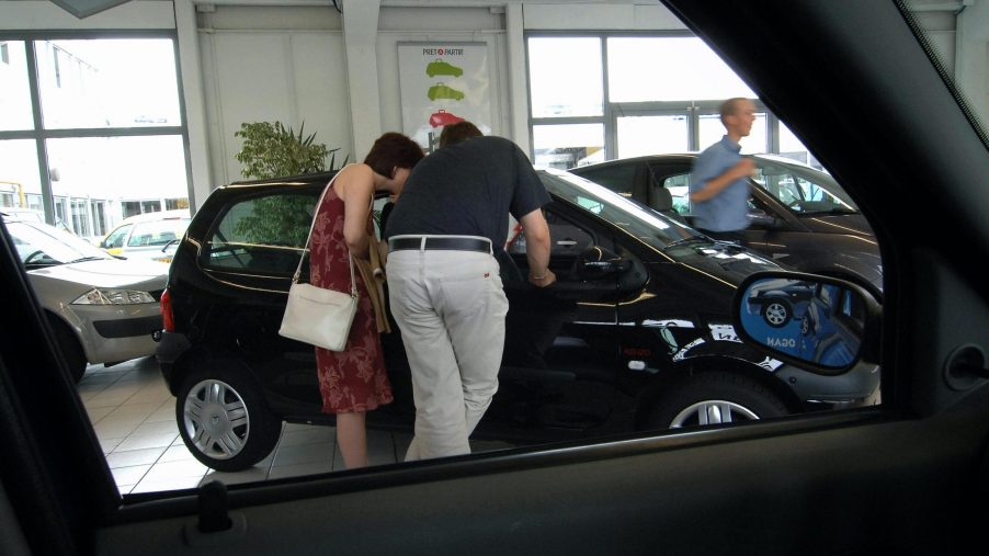 a couple checks out a car at a dealership
