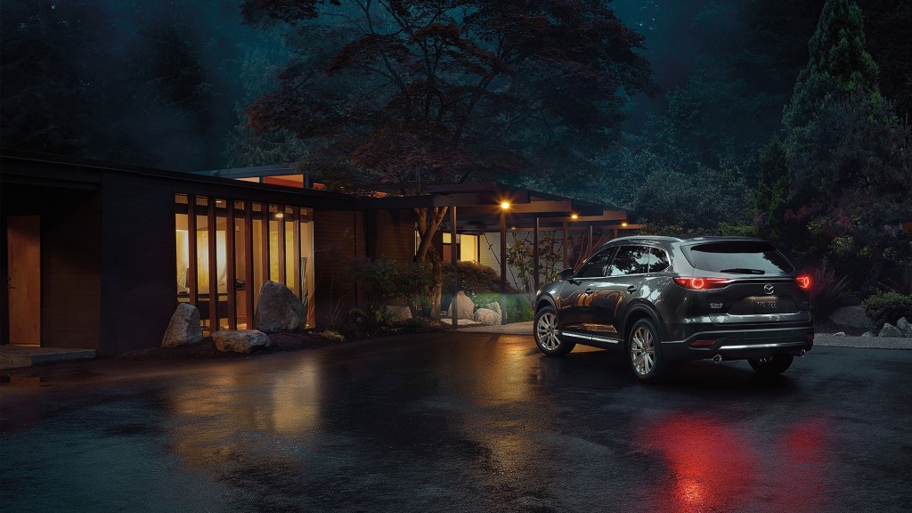A dark colored 2022 Mazda CX-9 parked outside of a house.