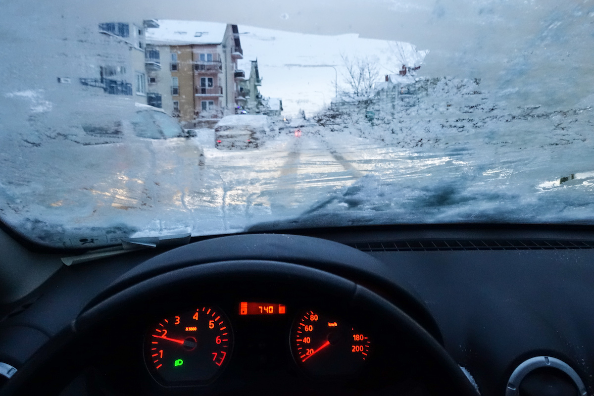 A view from the driver's seat of a car with a frozen car in the winter