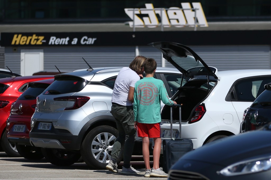 Tourists load their luggage in their rental car. 