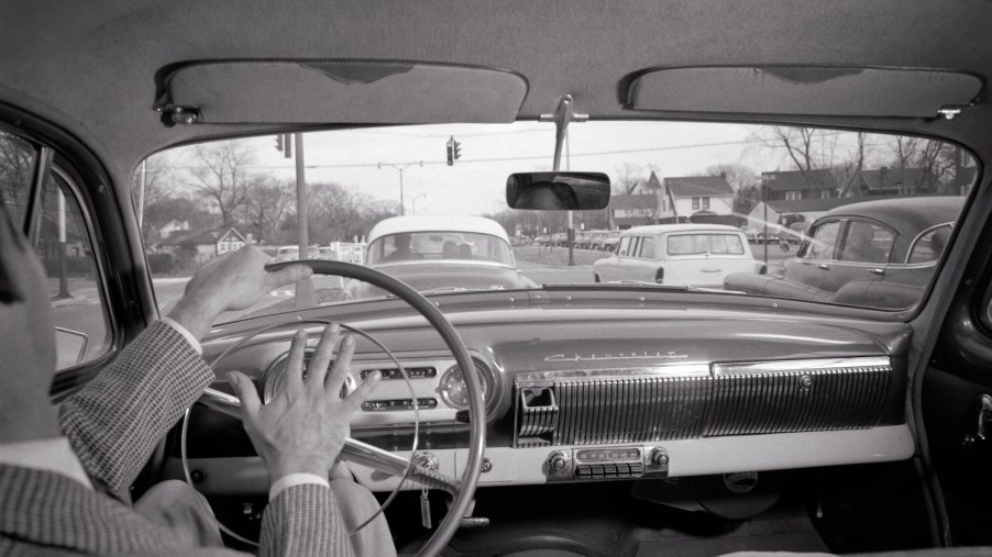 The driver of a vintage Chevrolet honking his horn at slow traffic.