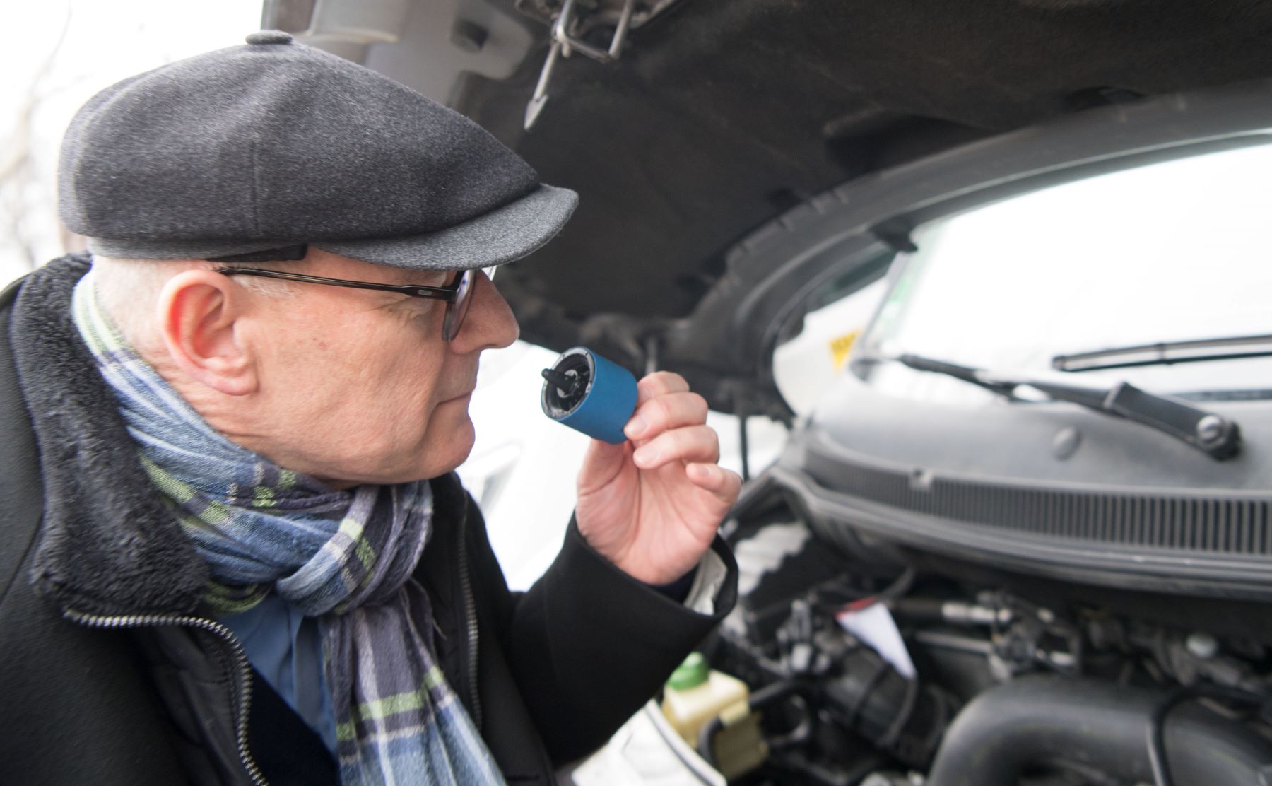 A man smelling car components during a diesel retrofitting of a VW T5 in Germany