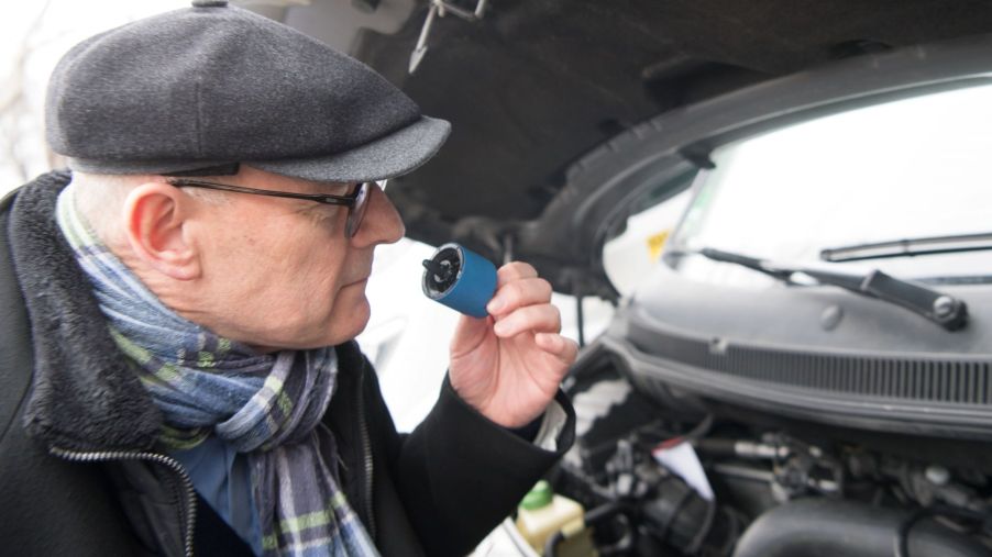 A man smelling car components during a diesel retrofitting of a VW T5 in Germany