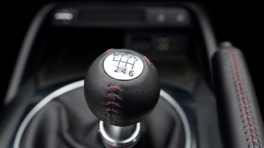 A black gear select from a manual transmission versus an automatic transmission with a silver plate.