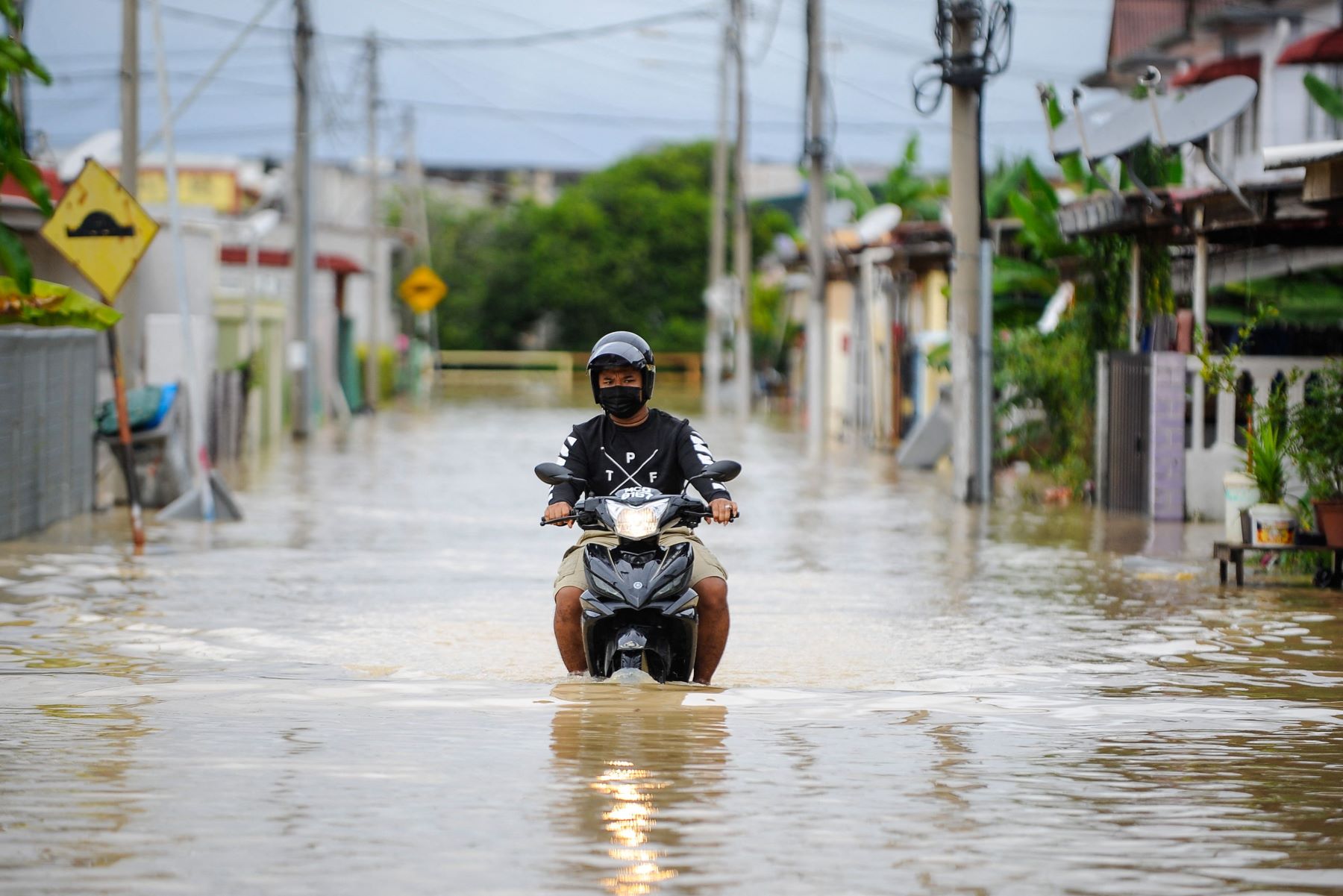 A man having problems driving his motorcycle through a flood after flooding in Malaysia