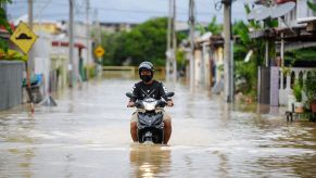 A man having problems driving his motorcycle through a flood after flooding in Malaysia