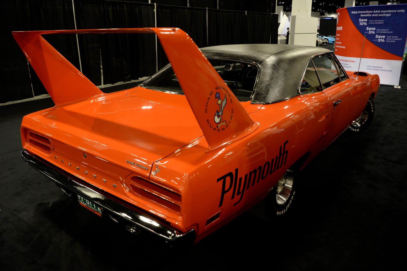 Side-angle rear view of a bright orange 1970 1970 Plymouth Roadrunner Super Bird on display at the Denver Auto Show. This American muscle car had a huge rear spoiler.