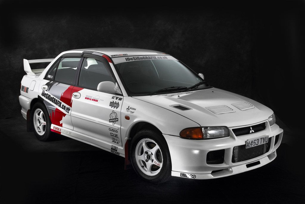 A white-with-red-black-and-gray-stripes 1995 Mitsubishi Lancer Evo III