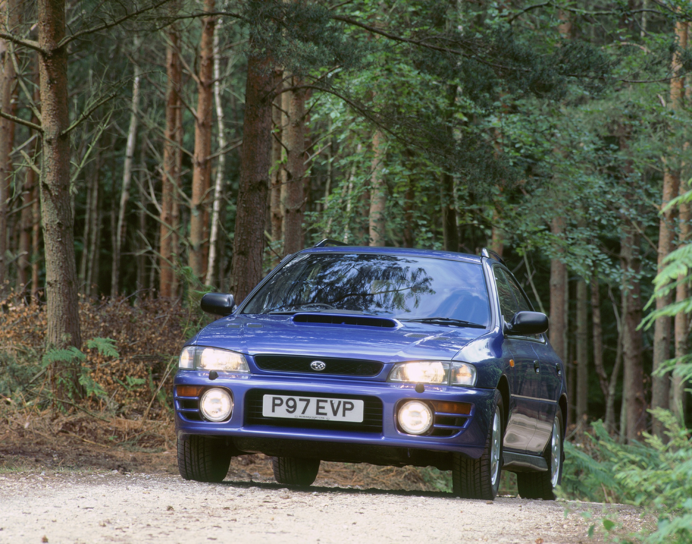 A blue 1997 UK-market GC8 Subaru Impreza WRX (Turbo 2000) in a forest