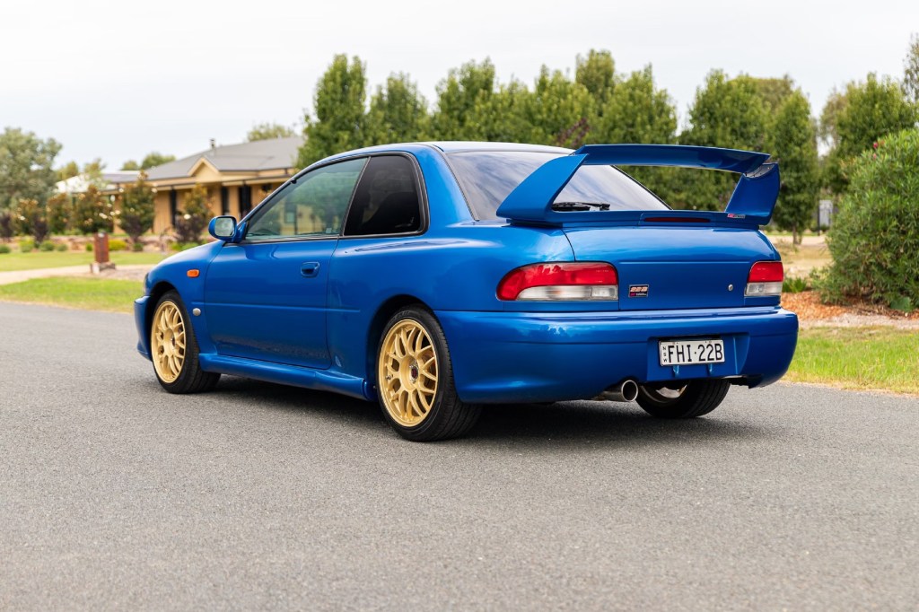 The rear 3/4 view of a blue 1998 Subaru Impreza 22B STi on an Australian street