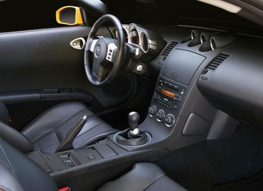 The black seats and dashboard of a 2005 Nissan 350Z Coupe with a manual