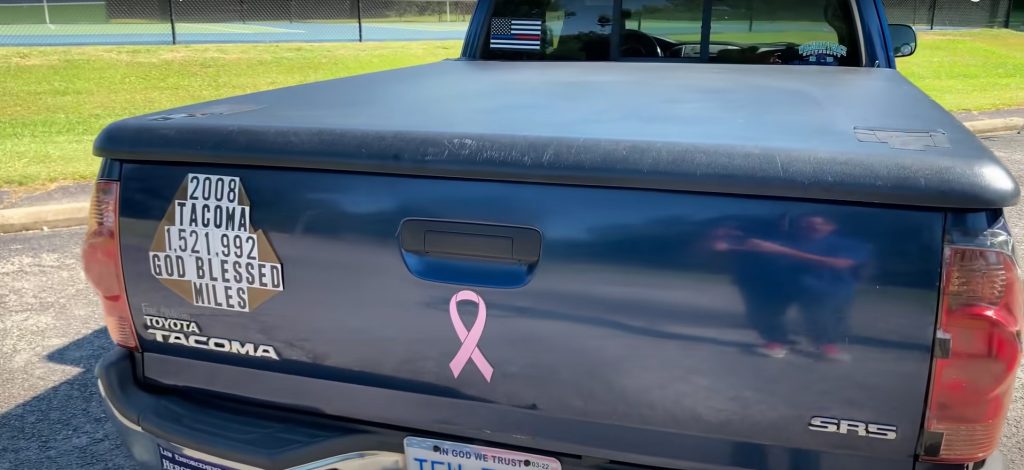 Tailgate of a blue pickup truck with a 1,521,992 god-blessed miles sticker.