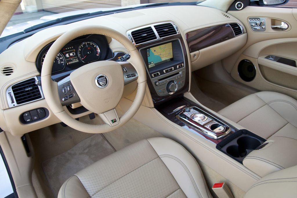 The tan-leather front seats and wood-trimmed dashboard of a 2011 Jaguar XKR Coupe