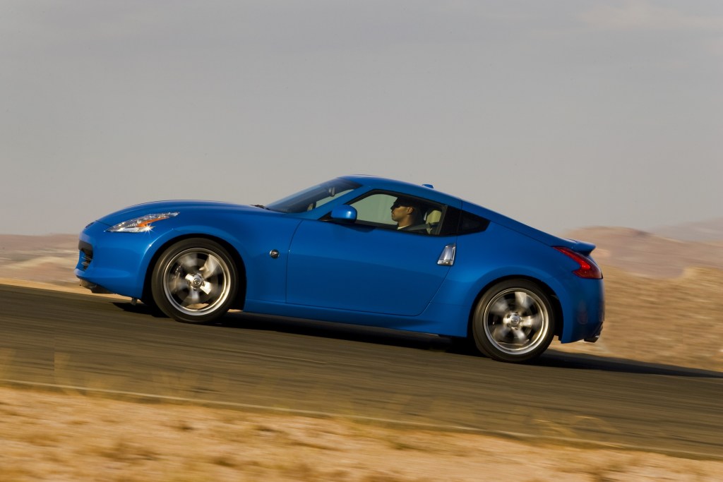 The side view of a blue 2012 Nissan 350Z Coupe driving on a desert track