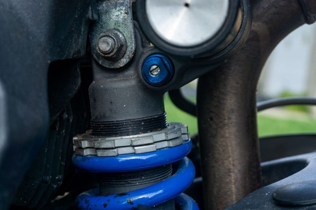 The blue compression adjustment screw, silver preload collar, and blue spring on a 2012 Triumph Street Triple R's rear shock