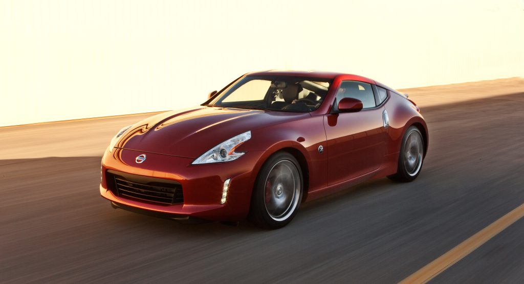 A red 2013 Nissan 370Z Coupe drives down a road