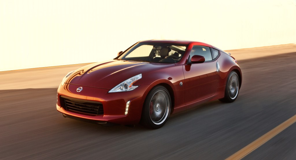 A red 2013 Nissan 370Z Coupe sports car drives down a street